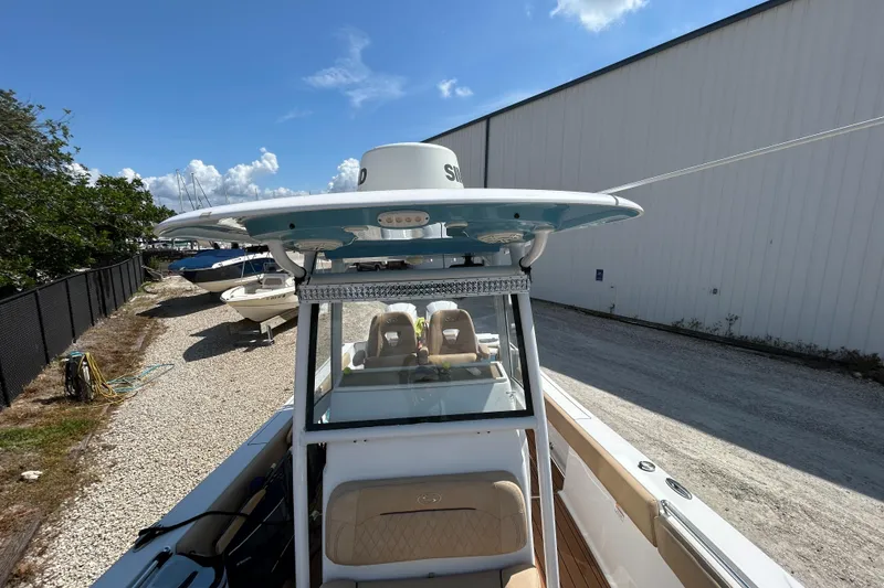 Slide: The Image of 2018 Sportsman 282 boat with T-top, parked outdoors on gravel near a warehouse. - 18