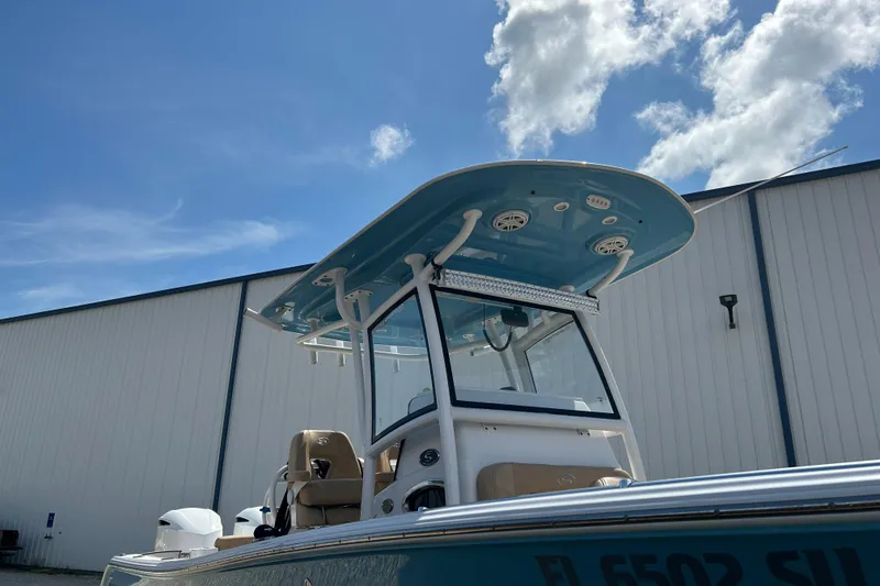 Slide: The Image of 2018 Sportsman 282 boat with blue T-top against a clear sky and warehouse background. - 32