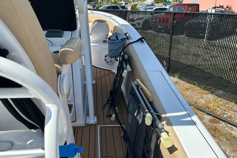 Slide: The Image of 2018 Sportsman 282 boat interior with fishing rods and seating, docked near a fence. - 5
