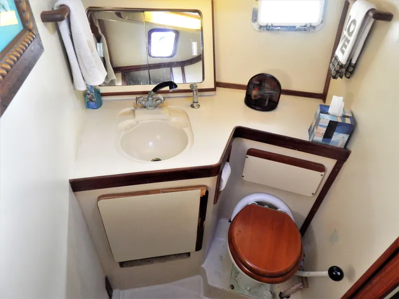 Slide: The Image of Compact bathroom in 1986 Irwin 43 Mk II Cruiser with sink, mirror, and wooden toilet seat. - 14