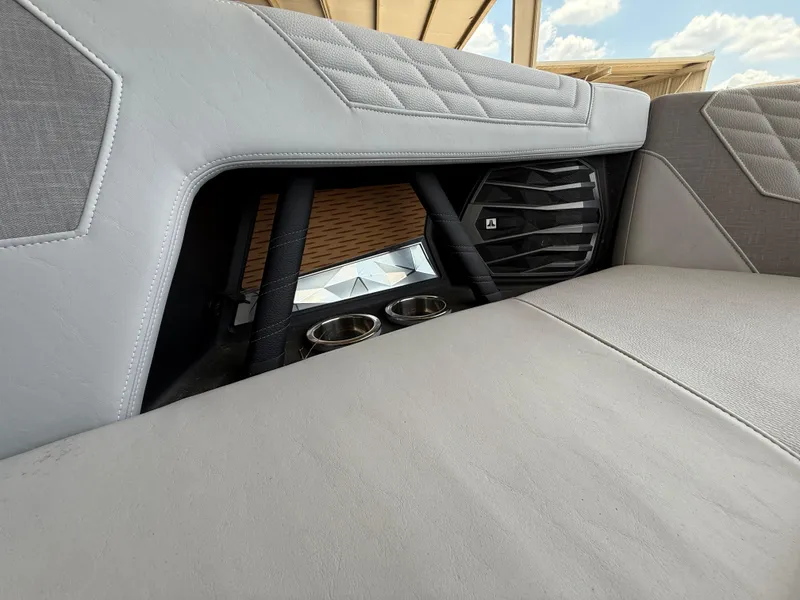 Slide: The Image of 2022 Nautique Super Air G23 interior with speaker and cup holders, featuring gray upholstery. - 28