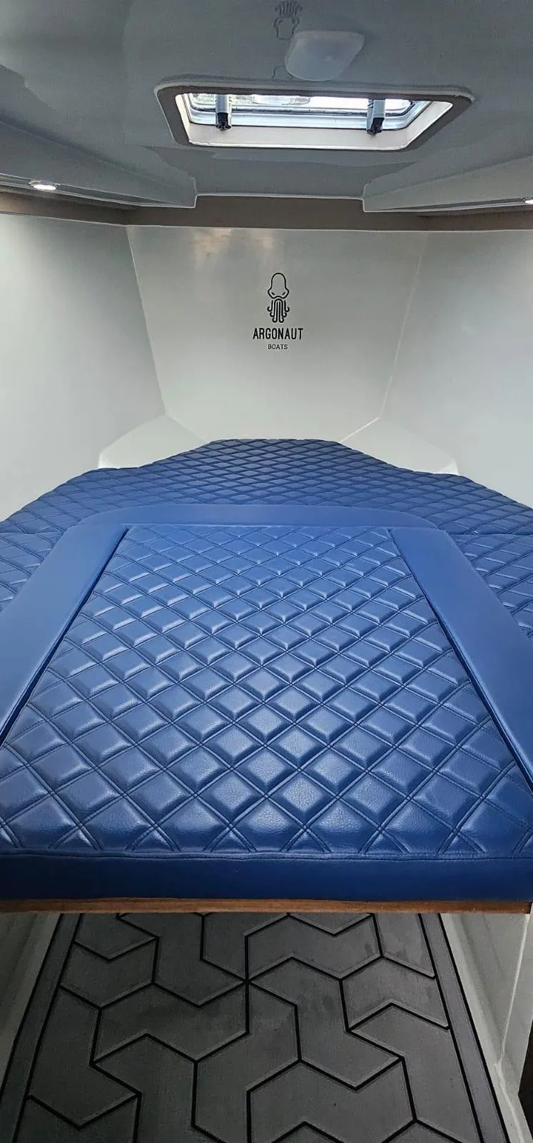 Slide: The Image of Interior of 2023 Argonaut 260 boat with blue quilted seating and overhead window. - 6