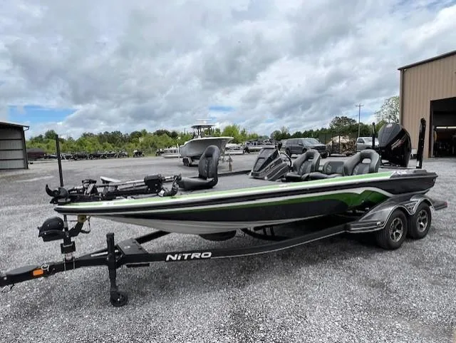 Slide: The Image of 2024 Nitro Z21 XL bass boat on trailer, parked outdoors under cloudy sky. - 3