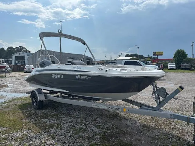 Slide: The Image of 2022 Hurricane SunDeck Sport 185 OB boat on trailer, parked outdoors under cloudy sky. - 2