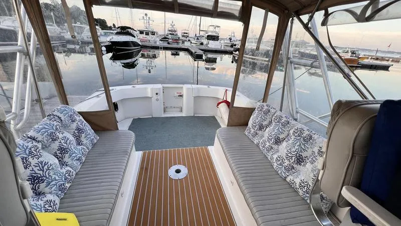 Slide: The Image of 2003 Mainship Pilot 30-II boat interior with cushioned seating, docked at a marina. - 11