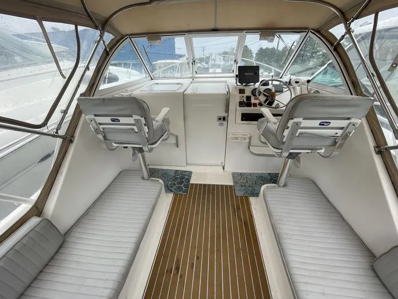 Slide: The Image of 2003 Mainship Pilot 30-II boat interior with helm, seating, and wooden flooring. - 16