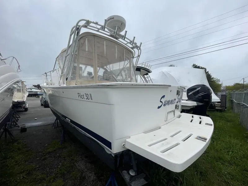 Slide: The Image of 2003 Mainship Pilot 30-II boat on land, rear view, overcast sky. - 17