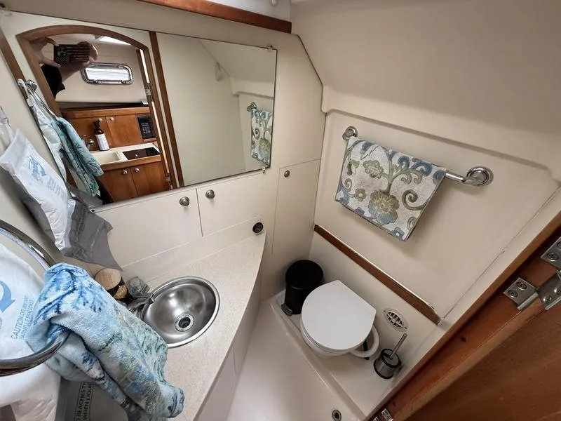 Slide: The Image of 2003 Mainship Pilot 30-II boat bathroom with sink, mirror, and toilet. - 4