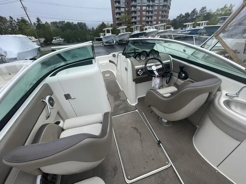 Slide: The Image of 2012 Sea Ray 260 Sundeck interior with seating, steering wheel, and dashboard in a marina setting. - 7