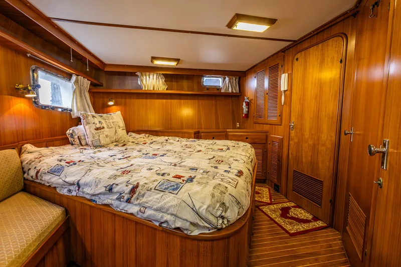 Slide: The Image of 1986 Kha Shing 37' yacht bedroom with wood paneling and nautical-themed bedding. - 15