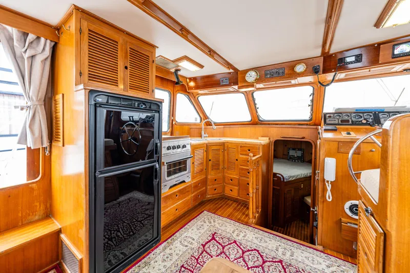 Slide: The Image of 1986 Kha Shing 37' yacht interior with wood paneling, kitchen, and navigation area. - 18