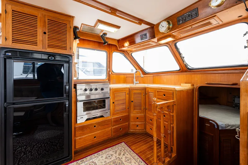 Slide: The Image of 1986 Kha Shing 37' yacht interior with wooden cabinetry and kitchen appliances. - 23