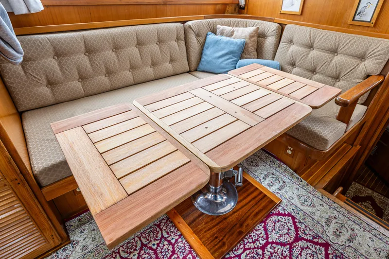 Slide: The Image of Interior of 1986 Kha Shing 37' yacht with wooden table and cushioned seating. - 37