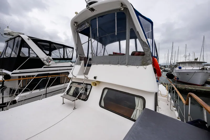 Slide: The Image of 1986 Kha Shing 37' yacht docked at marina, featuring upper deck and enclosed cabin. - 48