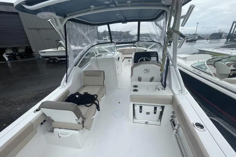 Slide: The Image of 2024 Edgewater 248CX boat interior with seating, helm, and storage, docked at marina. - 5