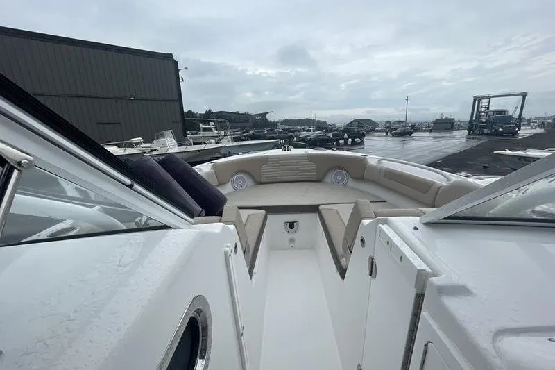 Slide: The Image of 2024 Edgewater 248CX boat interior with beige seating, docked at marina. - 9