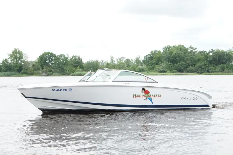 Slide: The Image of 2018 Cobalt 220S boat on a calm river with lush green trees in the background. - 1