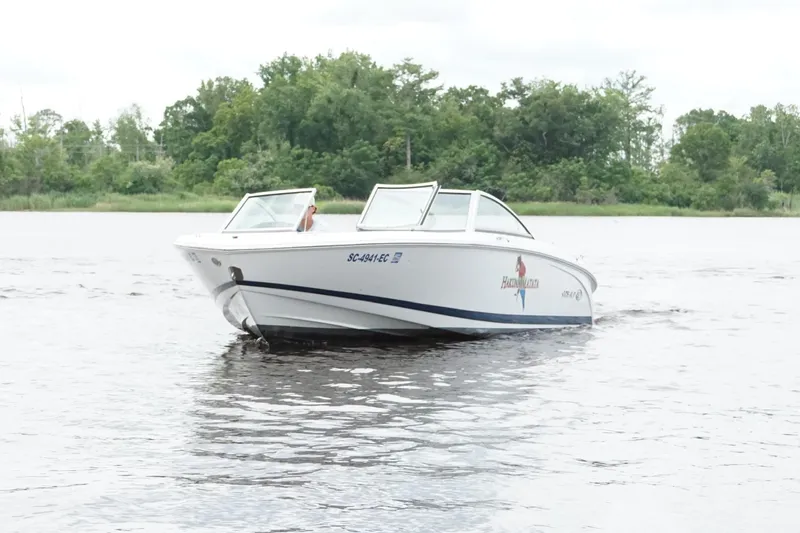 Slide: The Image of 2018 Cobalt 220S boat on a calm lake with lush green trees in the background. - 10