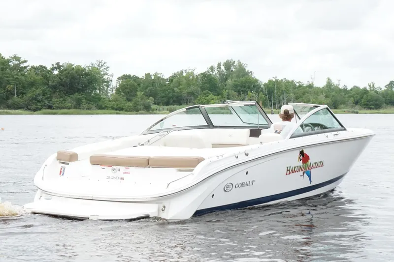 Slide: The Image of 2018 Cobalt 220S boat cruising on a calm lake with lush green trees in the background. - 14