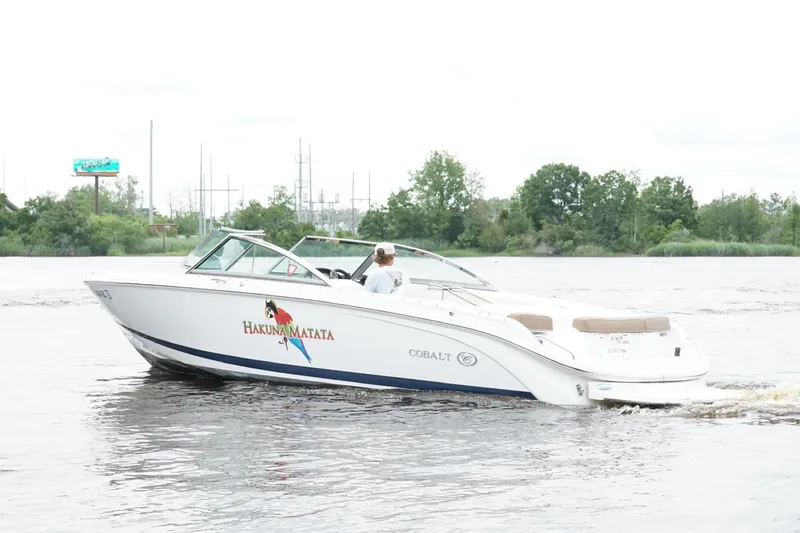 Slide: The Image of 2018 Cobalt 220S boat cruising on a river with lush green trees in the background. - 5