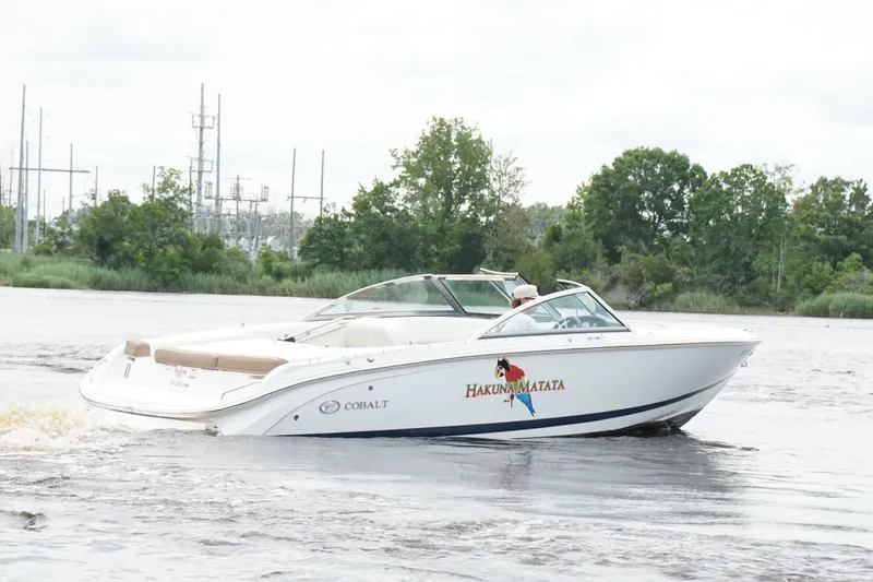 Slide: The Image of 2018 Cobalt 220S boat cruising on a river with lush green trees in the background. - 7