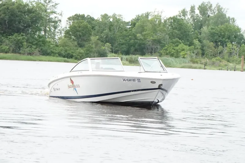 Slide: The Image of 2018 Cobalt 220S boat cruising on a calm lake with lush greenery in the background. - 8
