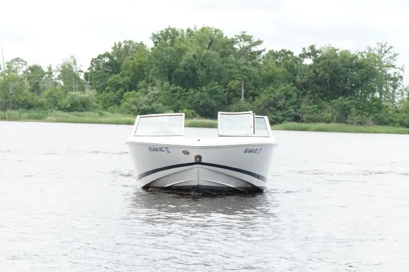 Slide: The Image of 2018 Cobalt 220S boat on a calm lake with lush green trees in the background. - 9