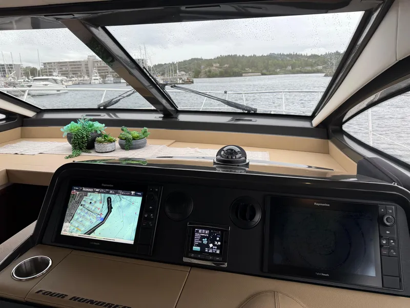 Slide: The Image of Helm of 2016 Sea Ray 400 Sundancer with navigation screens and scenic marina view. - 18