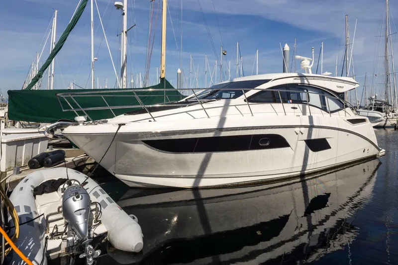 Slide: The Image of 2016 Sea Ray 400 Sundancer yacht docked at marina with inflatable boat nearby. - 51