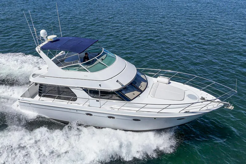 Slide: The Image of 2000 Carver 450 Voyager Pilothouse cruising on open water, showcasing sleek design and luxury. - 17