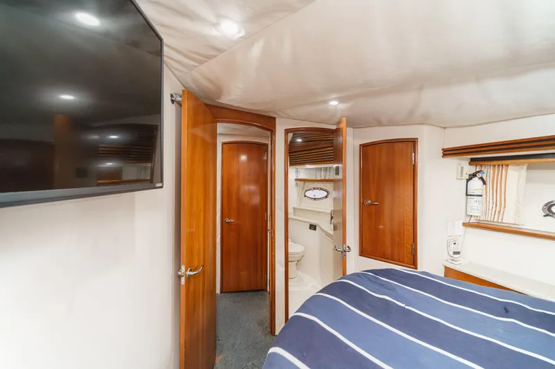 Slide: The Image of Interior of 2000 Carver 450 Voyager Pilothouse with wood doors and striped bedding. - 58