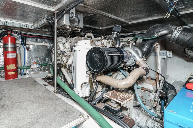 Slide: The Image of Engine room of a 2000 Carver 450 Voyager Pilothouse with visible components and fire extinguisher. - 61