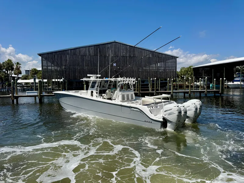Slide: The Image of 2022 Invincible 46 Catamaran in marina, featuring twin outboard engines, under clear blue sky. - 14