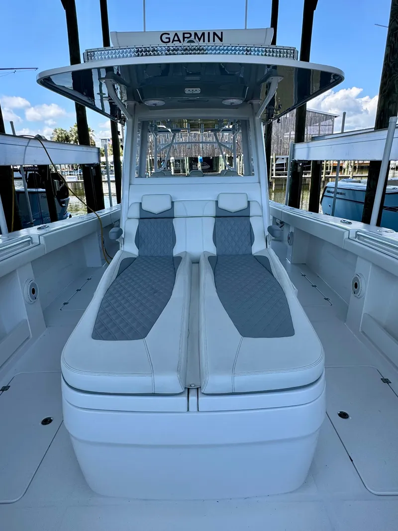 Slide: The Image of 2022 Invincible 46 Catamaran with cushioned seating and modern design in a marina setting. - 19