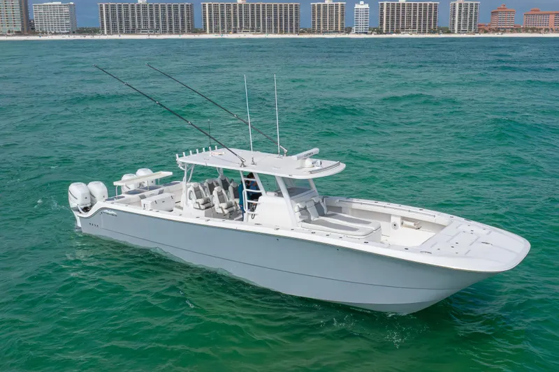 Slide: The Image of Invincible 46 Catamaran 2022 cruising on turquoise waters near a coastal cityscape. - 2