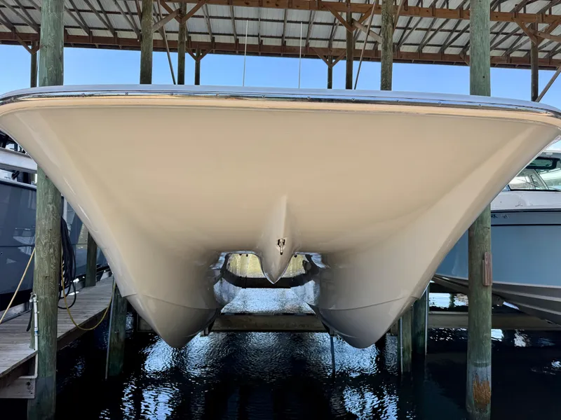 Slide: The Image of 2022 Invincible 46 Catamaran under a dock, showcasing its sleek hull design. - 34