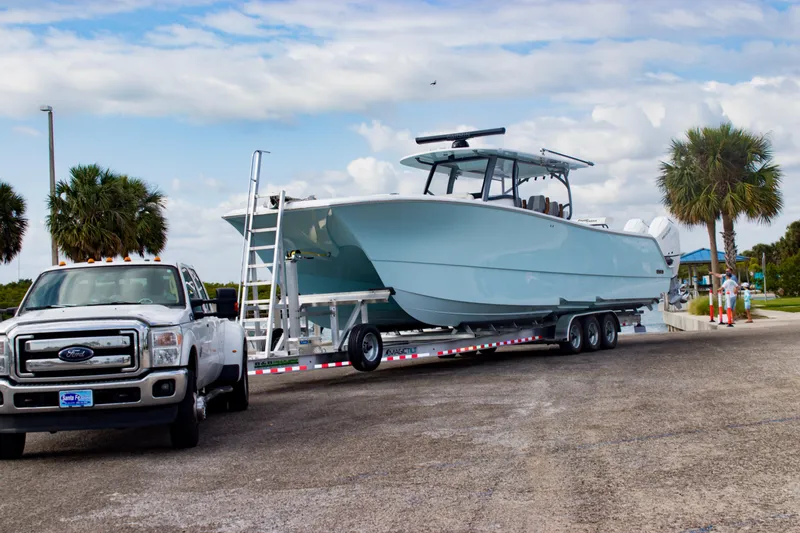 Slide: The Image of 2026 Front Runner 43 Catamaran on trailer, parked near palm trees and cloudy sky. - 39
