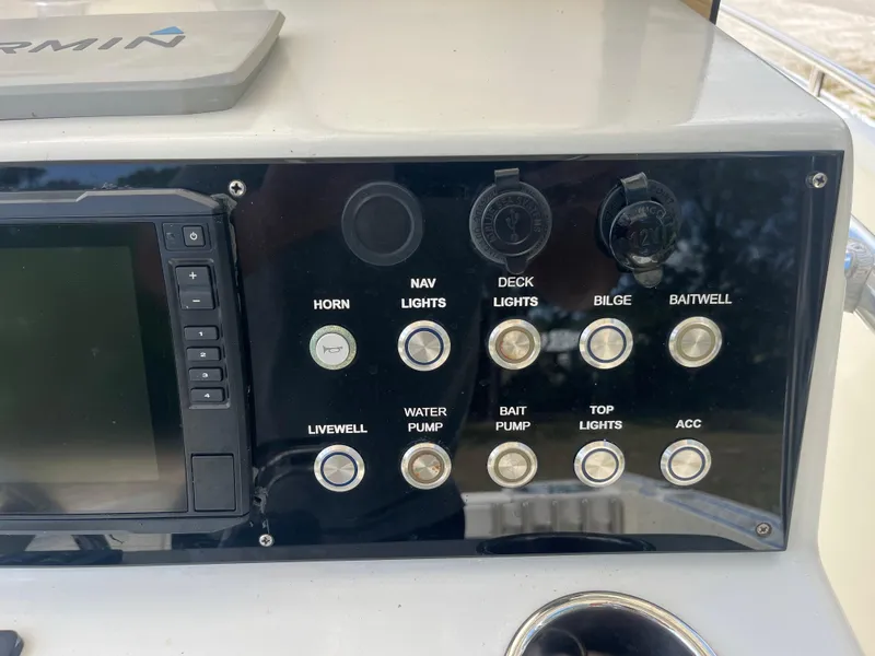 Slide: The Image of Control panel of a 1998 Blue Fin 25 Center Console boat with various switches and a Garmin device. - 7