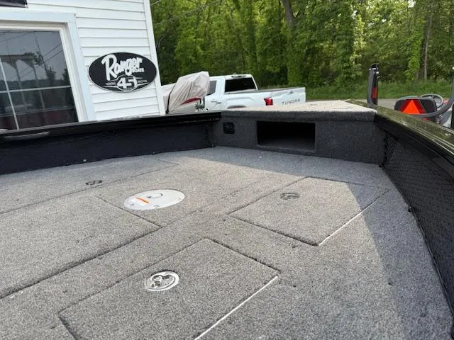 Slide: The Image of 2025 Crestliner 2050 Fish Hawk boat deck with storage compartments, parked near a building. - 6