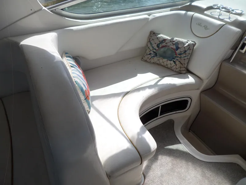 Slide: The Image of 2003 Sea Ray 280 Sundancer interior with cushioned seating and decorative pillows. - 10