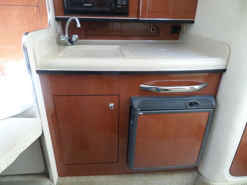 Slide: The Image of 2003 Sea Ray 280 Sundancer kitchenette with sink, cabinet, and mini-fridge. - 31