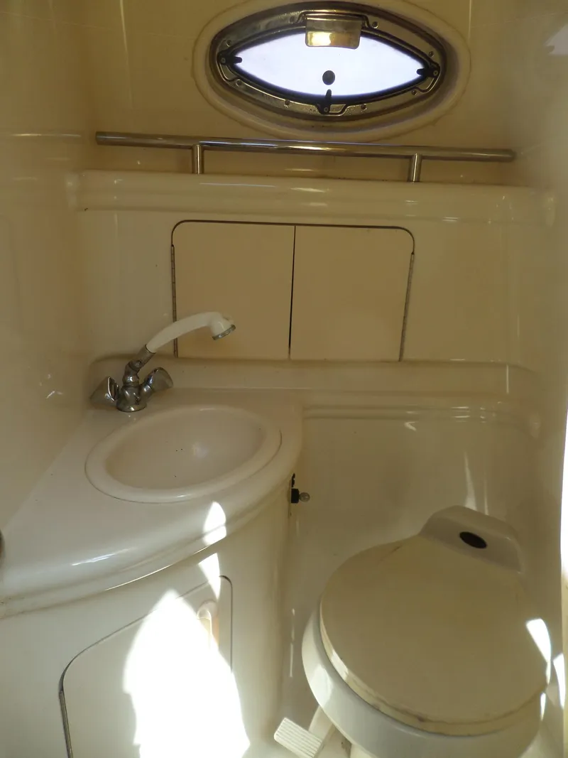 Slide: The Image of 2003 Sea Ray 280 Sundancer bathroom with sink, toilet, and porthole window. - 34