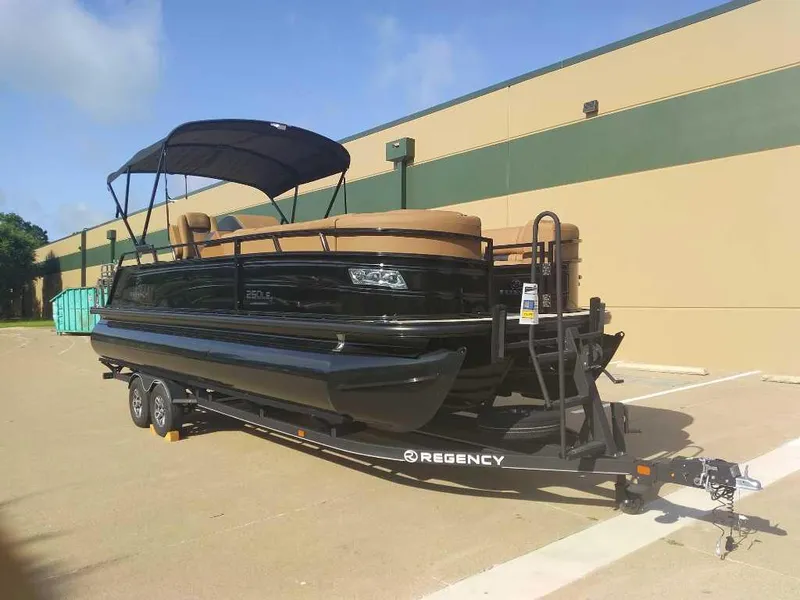 Slide: The Image of 2025 Regency 250 LE3 Sport pontoon boat on trailer, parked outdoors. - 1