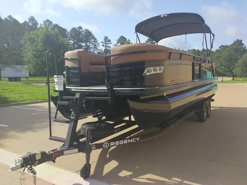 Slide: The Image of 2025 Regency 250 LE3 Sport pontoon boat on trailer, parked outdoors. - 6