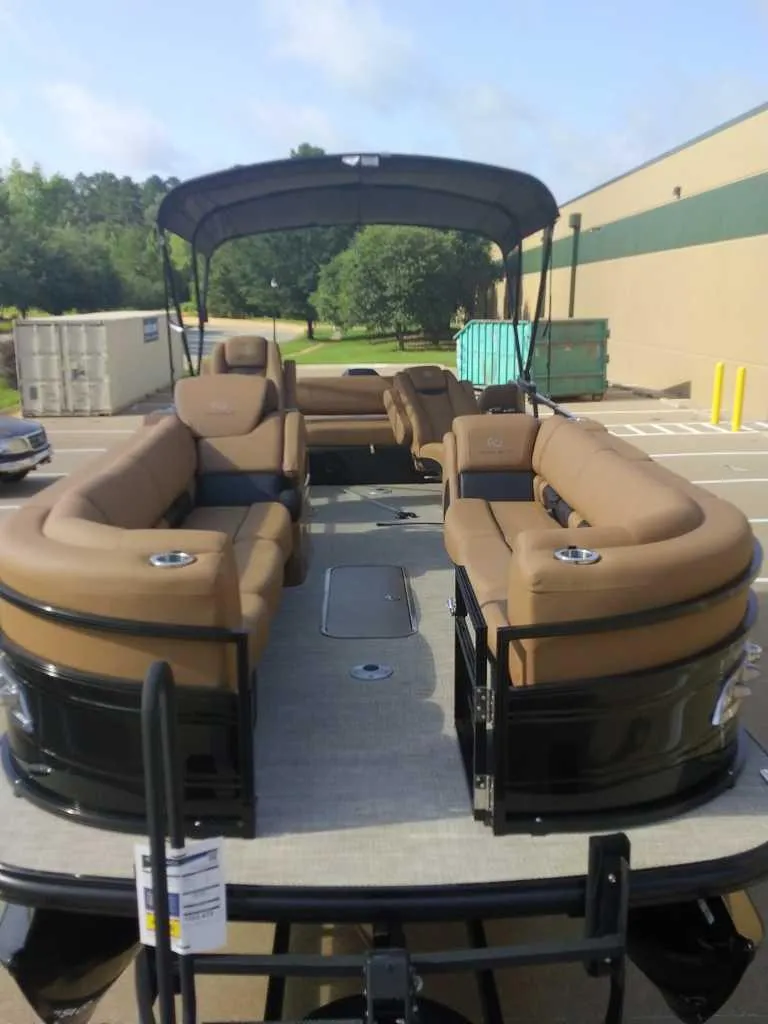 Slide: The Image of 2025 Regency 250 LE3 Sport pontoon boat with spacious seating and canopy in a parking lot. - 8
