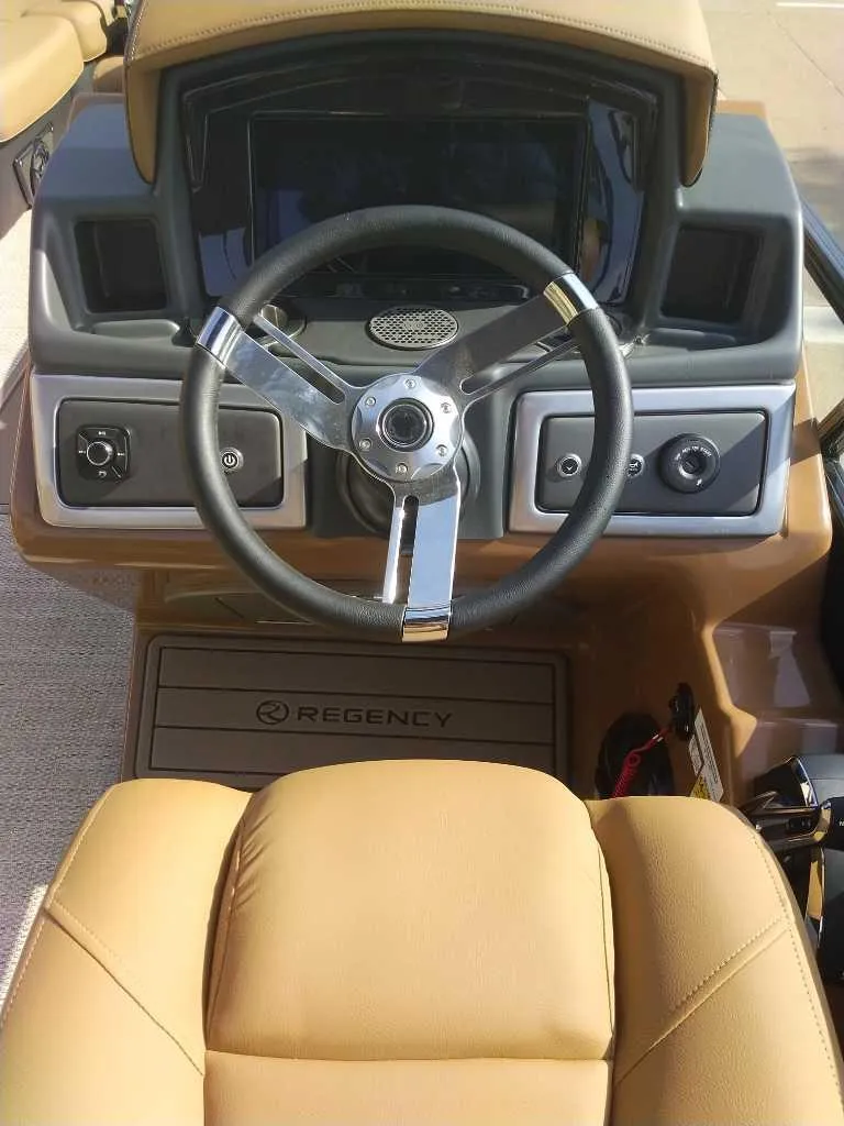Slide: The Image of 2025 Regency 250 LE3 Sport boat dashboard with steering wheel and controls. - 9