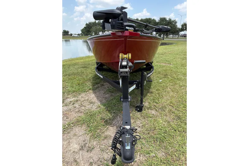 Slide: The Image of Red 2025 Tracker Super Guide V-16 T boat on trailer near a pond. - 32