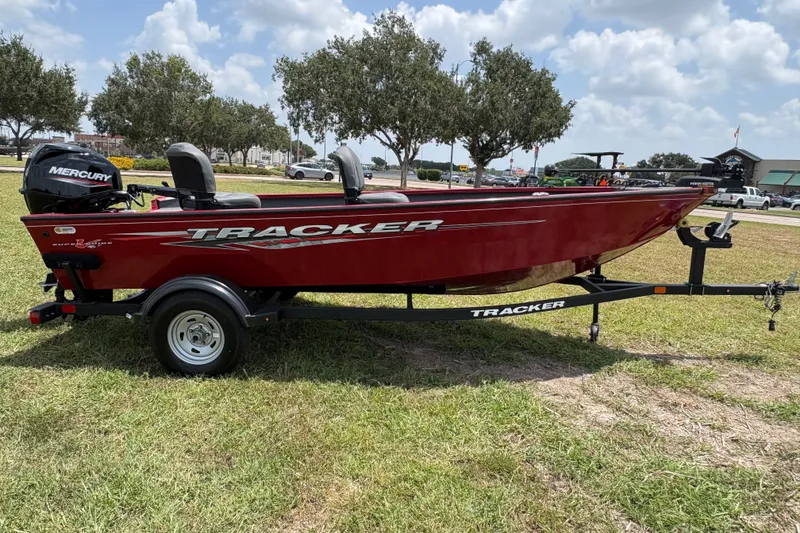 Slide: The Image of 2025 Tracker Super Guide V-16 T boat on trailer, red exterior, parked on grass. - 38