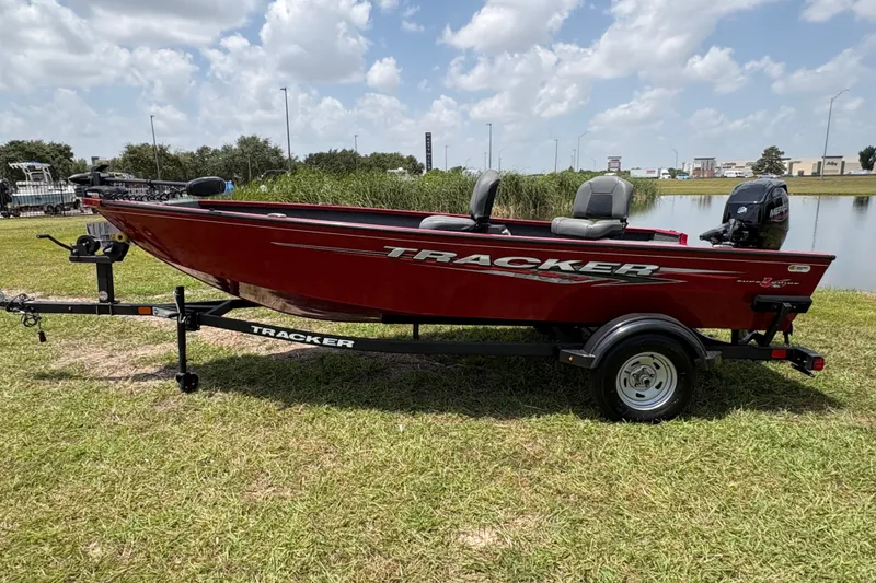 Slide: The Image of 2025 Tracker Super Guide V-16 T boat on trailer, red exterior, parked on grass. - 34