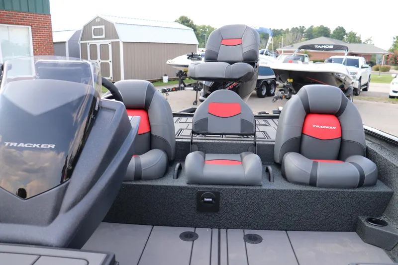Slide: The Image of 2025 Tracker Savage 215 boat interior with gray and red seating, parked outdoors. - 11